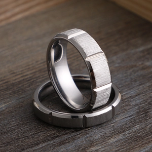 Industrial style brushed stainless steel rings with geometric grooves on wood surface