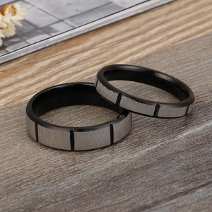 Brushed stainless steel black and silver couple rings set on natural wood background
