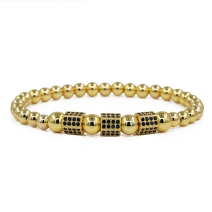 Dettaglio del bracciale dorato con perline e tre distanziatori quadrati in zirconi neri