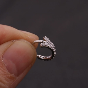 Macro shot of silver cartilage earring with micro-pave zircons held by fingers