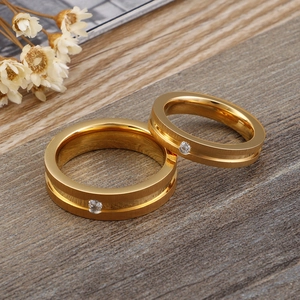 Frosted gold stainless steel couple rings set with zircons on a wooden background