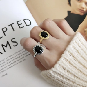 Close-up of 925 sterling silver rings with oval black onyx and gold beaded setting