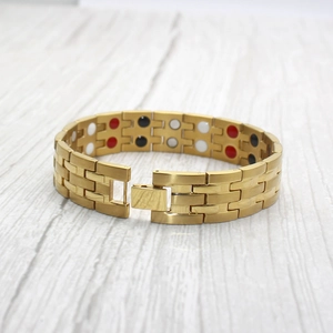 15mm gold stainless steel magnetic therapy bracelet displayed on a wooden surface