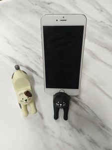 Close-up of cute cat-shaped resin phone holders in stretching poses on marble surface