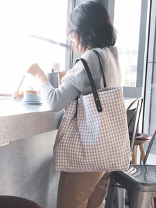 Detail of Japanese style gingham tote bag featuring black leather handles and metal rivets