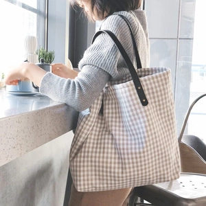 Side view of a vintage gingham cotton tote bag with long black leather shoulder straps