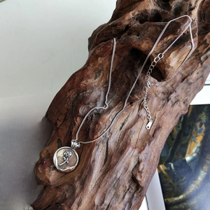Macro detail of silver rose coin pendant on wood with vintage book background