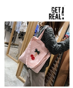 Close-up of pink canvas tote bag featuring cherry embroidery and green ribbon bow detail