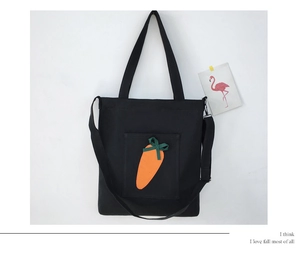 Close-up of black canvas tote bag featuring orange carrot embroidery and adjustable strap