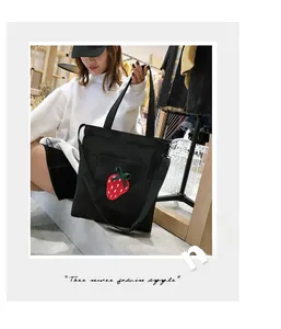 Detail of black canvas tote bag with strawberry embroidery and adjustable shoulder strap