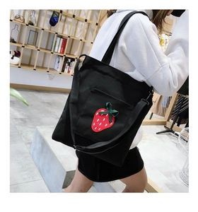 Detail of black canvas tote bag with red strawberry embroidery and long shoulder straps