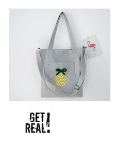 Detail of grey canvas tote bag featuring a pineapple embroidery and adjustable strap