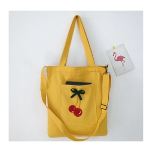 Detailed close-up of a yellow canvas tote bag with embroidered cherry and green bow