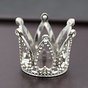 Close-up of a silver alloy cake topper crown with sparkling rhinestones and metal details