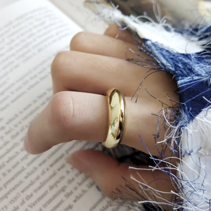 Close-up of a wide polished gold dome ring on finger with a minimalist mirror finish style