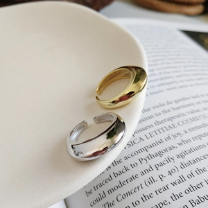 Detail of minimalist 925 sterling silver open rings in gold and silver on a white plate