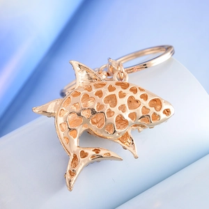 Golden shark keychain with hollow heart patterns shown on a soft blue background