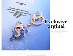 Detail of shark keychain with blue and white crystals on a gold-tone metal base