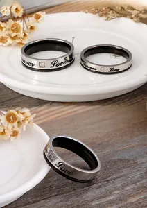 Détail de bagues de couple en titane argent et noir avec gravure Forever Love et zircon