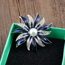 Macro shot of silver floral brooch with blue enamel petals, rhinestones and a center pearl