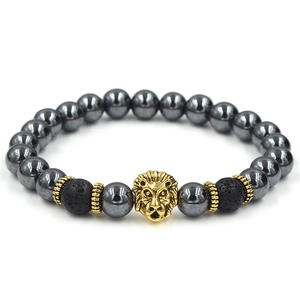 Macro view of a gold lion head bead on a men's hematite and lava stone bracelet