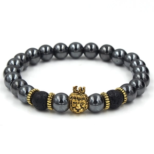Macro detail of men's hematite beaded bracelet with a golden crown lion head charm