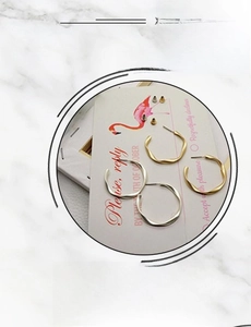 Detail of matte gold and silver twisted C-shaped wavy hoop earrings set on marble