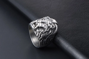 Close-up of vintage silver lion head ring for men on a black leather surface