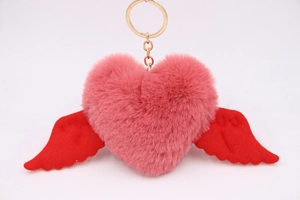 Detail of pink plush heart keychain with red wings and golden metal ring fastener