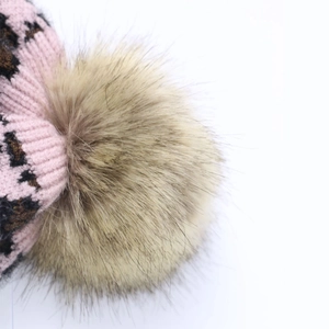Close-up of pink leopard print knit hat featuring a fluffy faux fur pom-pom detail