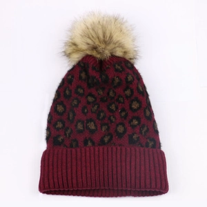 Detailed knit texture of burgundy leopard print beanie with thick ribbed cuff and pom
