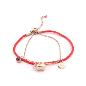 Red cord bracelet with rose gold pig charm and Fu character pendant on white background
