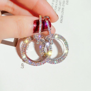Macro detail of double-loop earrings with iridescent crystals on a silver setting