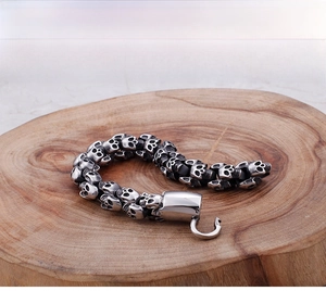 Macro detail of gothic punk skull link bracelet with smooth metal hook clasp on wood