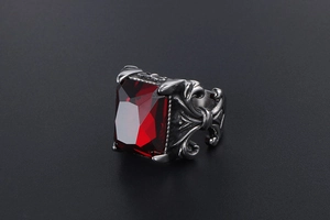 Detail of Gothic titanium steel ring featuring an ornate floral pattern and a large red stone