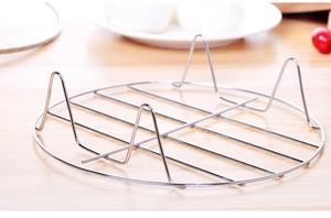 Detail of a stainless steel steaming rack with three stable legs on a wooden kitchen counter