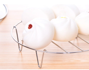 Macro view of steaming rack with white buns on a textured wooden tabletop surface