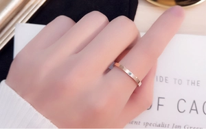 Close-up of a slim rose gold ring featuring a single square-cut diamond on hand