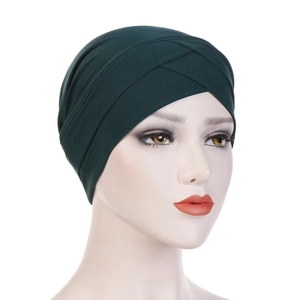 Close-up of the dark green elastic turban hat featuring a cross-front knot design