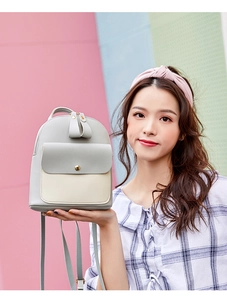 Close-up of contrast grey and off-white women's backpack with gold zippers and hardware