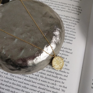 Detailed macro view of a vintage gold coin pendant necklace on artistic mineral stone