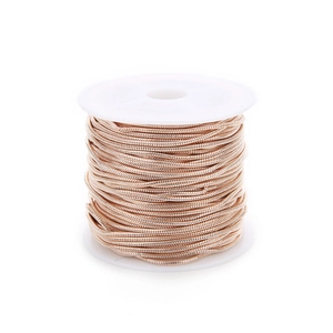 Detail of rose gold snake chain on white spool for jewelry making and DIY projects