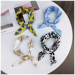 Flat lay of four satin square scarves with geometric, polka dot, and leopard prints on tray