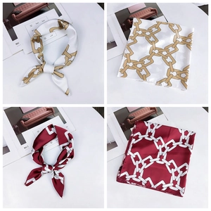Detail of chain print silk scarves in white and burgundy with elegant satin texture
