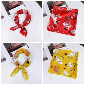 Detailed view of floral and butterfly print silk square scarves in red and yellow tones