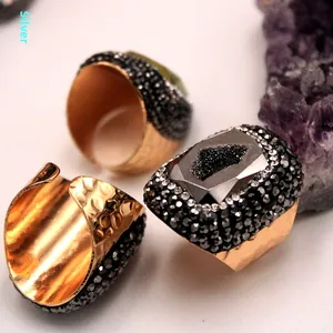Vista macro de anillo dorado grueso con acabado martillado y cristal druzy grisáceo