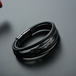 Macro shot of multi-layer black braided leather bracelet with gunmetal feather charm