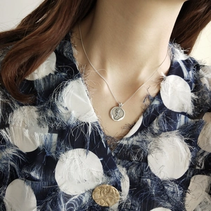 Macro detail of silver rose embossed pendant necklace worn on neck with vintage art style