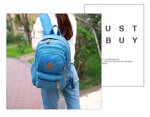 Outdoor shot of a blue canvas backpack featuring brown leather accents and multiple pockets