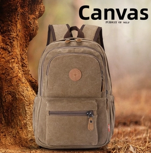 Outdoor close-up of brown canvas backpack with leather patch leaning on a tree trunk